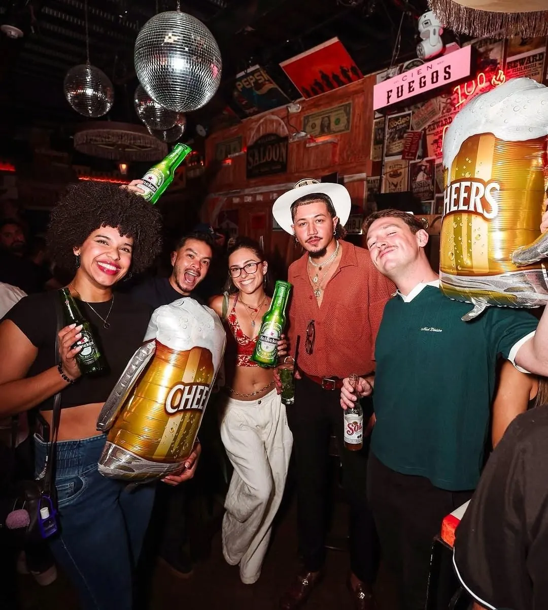 Guests with beers and cheers balloons in a lively Medellín bar
