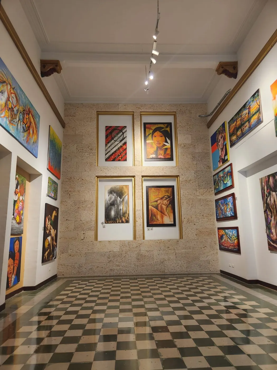 A downtown art gallery room with paintings on stone walls