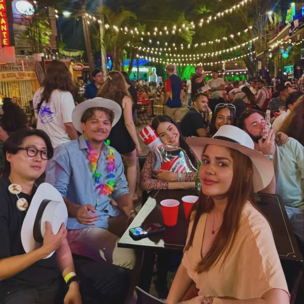 Guests in hats at an outdoor bar under string lights in Provenza