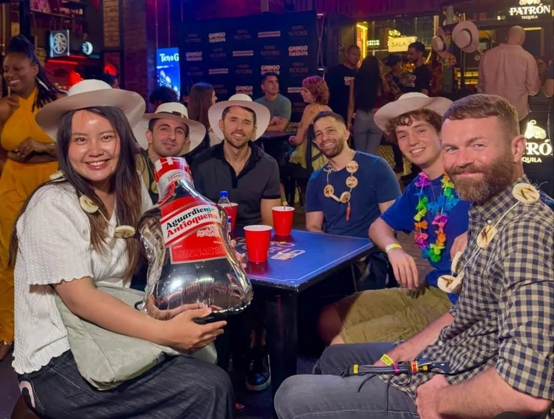 Guests with an aguardiente bottle balloon at a Medellín bar